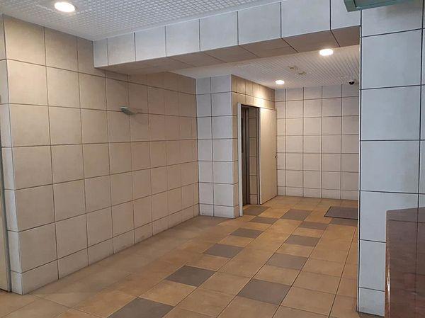 【エントランス】ホワイトタイルの壁とベージュの松葉模様の床のコラボの美しいエレベーターホール